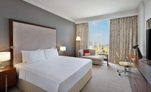Doubletree By Hilton Doha - Al Sadd في الدوحة: غرفة فندقية بسرير كبير ونافذة