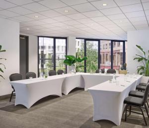 a conference room with white tables and chairs and windows at C. Baldwin, Curio Collection by Hilton in Houston