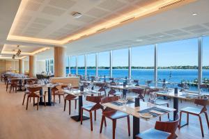 um restaurante com mesas e cadeiras e vista para o oceano em Doubletree By Hilton Perth Waterfront em Perth