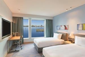 a hotel room with two beds and a desk and a window at Doubletree By Hilton Perth Waterfront in Perth