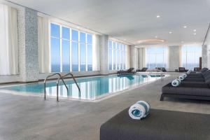 eine Hotellobby mit einem Pool mit Fenstern in der Unterkunft Aleph Doha Residences, Curio Collection By Hilton in Doha
