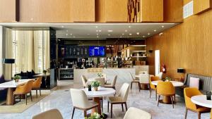 um restaurante com mesas e cadeiras e um bar em Aleph Doha Residences, Curio Collection By Hilton em Doha
