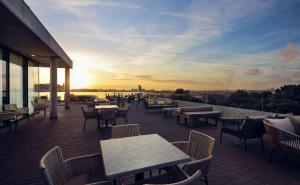a patio with tables and chairs and the sunset at Boeira Garden Hotel Porto Gaia, Curio Collection by Hilton in Vila Nova de Gaia
