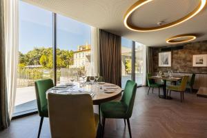 uma sala de jantar com mesas e cadeiras e uma grande janela em Boeira Garden Hotel Porto Gaia, Curio Collection by Hilton em Vila Nova de Gaia
