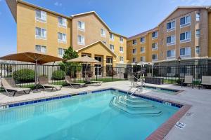 a swimming pool with chairs and a building at Homewood Suites by Hilton Albuquerque Airport in Albuquerque
