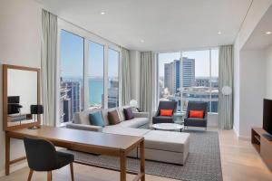 a living room with a couch and a large window at Aleph Doha Residences, Curio Collection By Hilton in Doha