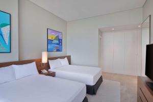Giường trong phòng chung tại Aleph Doha Residences, Curio Collection By Hilton