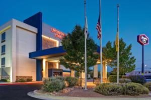 un edificio de oficinas con dos banderas delante en Hampton Inn Albuquerque - University/Midtown, en Albuquerque