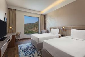 een hotelkamer met 2 bedden en een groot raam bij DoubleTree By Hilton Jaipur Amer in Jaipur