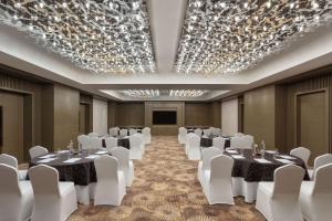 een vergaderzaal met tafels en witte stoelen en een podium bij DoubleTree By Hilton Jaipur Amer in Jaipur