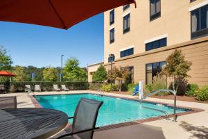 een zwembad met een tafel en stoelen naast een gebouw bij Hampton Inn & Suites Birmingham/280 East-Eagle Point in Hoover