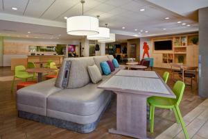 Home2 Suites by Hilton Nashville Vanderbilt, TN في ناشفيل: غرفة معيشة مع أريكة وطاولات وكراسي