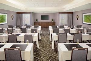 a conference room with tables and chairs and a screen at Embassy Suites by Hilton Boston Marlborough in Marlborough