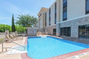 a swimming pool with chairs next to a building at Hampton Inn Brownwood in Brownwood