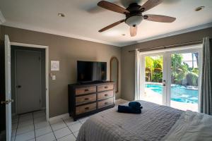 a bedroom with a bed with a ceiling fan and a television at Tropical Paradise in Fort Lauderdale