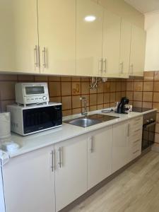 een keuken met witte kasten, een magnetron en een wastafel bij Guest House “Casa da avó Tina” in Barreiro