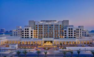 a large white building with palm trees in front of it at Hilton Abu Dhabi Yas Island in Abu Dhabi