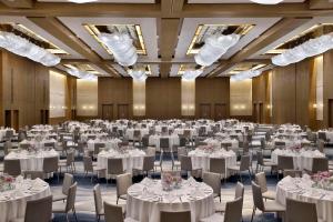 um grande salão de banquetes com mesas e cadeiras brancas em Hilton Abu Dhabi Yas Island em Abu Dhabi