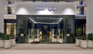 een ingang van een gebouw met een hiltonume teken erop bij Hilton Abu Dhabi Yas Island in Abu Dhabi