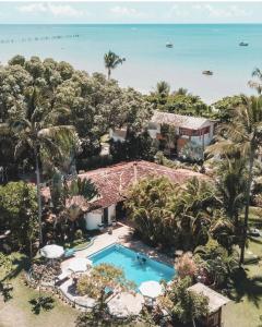 uma vista aérea de um resort com uma piscina e o oceano em Pousada Villa Cumuru em Cumuruxatiba