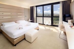 ボローニャにあるベスト ウェスタン プラス タワー ホテル ボローニャのベッドルーム(白いベッド1台、大きな窓付)