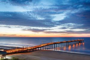 a pier stretches out over the ocean at sunset at DoubleTree Resort by Hilton Myrtle Beach Oceanfront in Myrtle Beach
