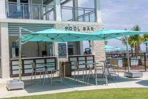 un bar junto a la piscina con mesas, sillas y sombrillas en DoubleTree Resort by Hilton Myrtle Beach Oceanfront en Myrtle Beach