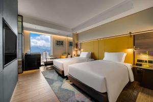 ein Hotelzimmer mit 2 Betten und einem TV in der Unterkunft Hotel Resonance Taipei, Tapestry Collection by Hilton in Taipeh
