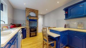 a blue kitchen with blue cabinets and a counter top at Charming 3 Bed Bungalow Parking & Wifi Business and Leisure by Jesswood Properties in Hinckley