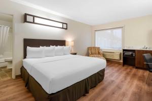 a hotel room with a large bed and a bathroom at Villa Inn & Suites - SureStay Collection by Best Western in Hearst