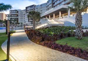 una passerella di fronte a un edificio con palme di Embassy Suites By Hilton Aruba Beach Resort a Palm Beach