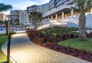 einen Gehweg vor einem Gebäude mit Palmen in der Unterkunft Embassy Suites By Hilton Aruba Resort in Palm-Eagle Beach