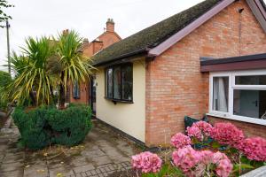 a brick house with pink flowers in front of it at Charming 3 Bed Bungalow Parking & Wifi Business and Leisure by Jesswood Properties in Hinckley