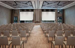 迪拜DoubleTree by Hilton Dubai M Square Hotel & Residences的一个空的会议室,有白色的椅子和空白的屏幕 更多37张照片