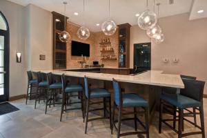 Homewood Suites By Hilton Orlando Flamingo Crossings, Fl في أورلاندو: مطبخ كبير مع بار مع كراسي وأضواء