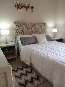 a bedroom with a large bed with two tables and two lamps at Infinit Home Duplex entero in Termas de Río Hondo