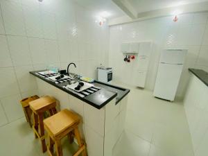 a white kitchen with a counter and a refrigerator at Apartamentos C7 in Cunha