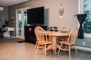 a dining room table with three chairs and a flat screen tv at Sun Chaser Bay in Carrying Place