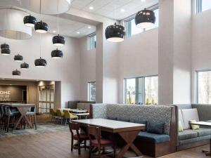 a waiting room with a couch and tables and chairs at Hampton Inn Redmond Bend Airport in Redmond