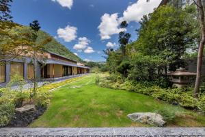 a green yard in front of a building with trees at ROKU KYOTO, LXR Hotels & Resorts in Kyoto