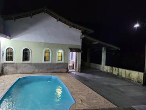 a swimming pool in front of a house at night at Chácara dos Sonhos em Mairiporã in Mairiporã