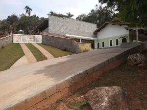 a house with a retaining wall next to a driveway at Chácara dos Sonhos em Mairiporã in Mairiporã