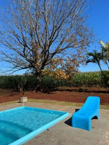 a blue bench sitting next to a swimming pool at Jardim D’Jully in Santa Terezinha de Itaipu