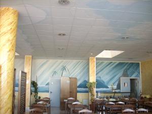 a dining room with tables and chairs and a painting on the wall at Il Bivio Hotel in Carmagnola +6 photos