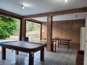 una stanza con tavolo da ping pong e muro di mattoni di Chácara dos Sonhos em Mairiporã a Mairiporã