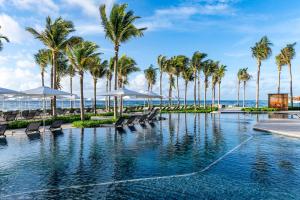 uma piscina na praia com palmeiras e cadeiras em Hilton Tulum Riviera Maya All-Inclusive Resort em Tulum
