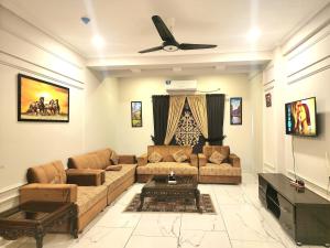 a living room with a couch and a ceiling fan at The Chromatic Apartments Bahria Town in Rawalpindi
