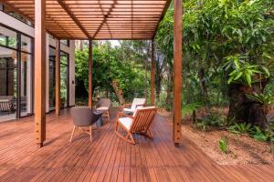 een houten terras met stoelen en tafels op een huis bij Botanika Osa Peninsula, Curio Collection By Hilton in Puerto Jiménez