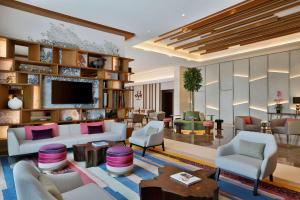 DoubleTree by Hilton Sharjah Waterfront Hotel And Residences في الشارقة: غرفة معيشة مليئة بالأثاث وتلفزيون