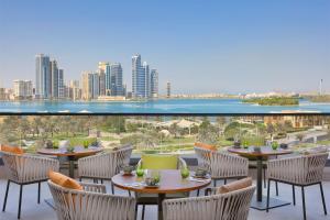 DoubleTree by Hilton Sharjah Waterfront Hotel And Residences في الشارقة: فناء به طاولات وكراسي ومطل على المدينة